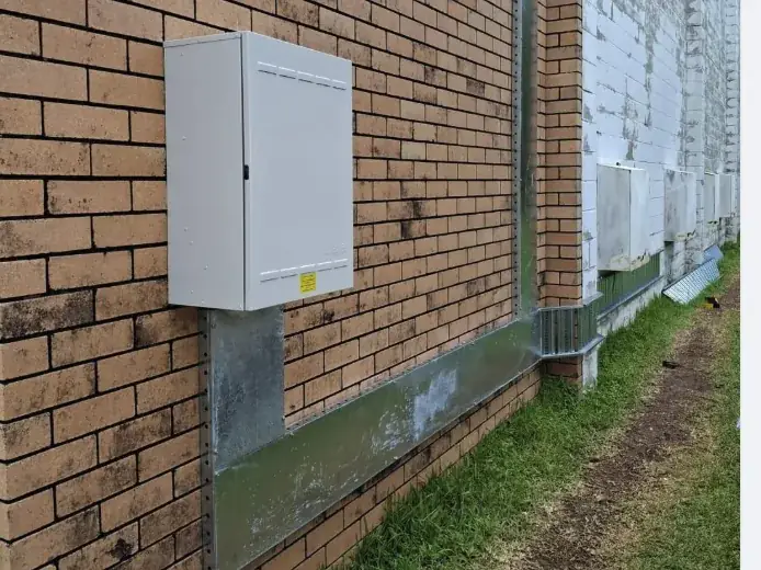 Exterior electrical cabinet and galvanised cable tray installation on a brick wall